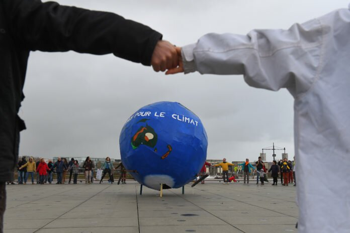 People make a circle around a makeshift Earth during a march for the climate in Bordeaux, southwestern France on December 8, 2018. - Thousands of people were participating today in climate marches in several cities in France, including a portion wearing yellow vests, with slogans calling for fighting in the same breath against the 