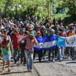Honduran migrants take part in a new caravan heading to the US with Honduran and Guatemalan national flags in Quezaltepeque, Chiquimula, Guatemala on October 22, 2018. - US President Donald Trump on Monday called the migrant caravan heading toward the US-Mexico border a national emergency, saying he has alerted the US border patrol and military.