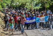Honduran migrants take part in a new caravan heading to the US with Honduran and Guatemalan national flags in Quezaltepeque, Chiquimula, Guatemala on October 22, 2018. - US President Donald Trump on Monday called the migrant caravan heading toward the US-Mexico border a national emergency, saying he has alerted the US border patrol and military.