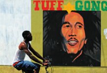 (FILES) In this file photo taken on February 8, 2009 a man pedals past a mural of late musician Bob Marley in Kingston. - Reggae music, whose chill, lilting grooves won international fame thanks to artists like Bob Marley, on November 29, 2018 secured a coveted spot on the United Nations' list of global cultural treasures.