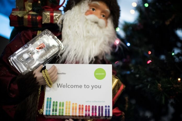 This illustration picture shows a saliva collection kit for DNA testing displayed in the arms of a Father Christmas doll in Washington, DC on December 19, 2018 as Americans are increasingly offering those tests to relatives during the Holiday season. - Between 2015 and 2018, sales of DNA test kits boomed in the United States and allowed websites to build a critical mass of DNA profiles. The four DNA websites that offer match services -- Ancestry, 23andMe, Family Tree DNA, My Heritage -- today have so many users that it is rare for someone not to find at least one distant relative.